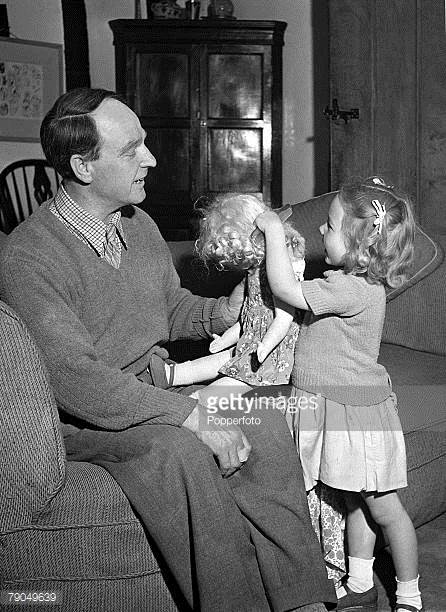 English Sculptor Henry Moore plays with his young daughter who is pictured untangling her doll's hair with a comb, at their home